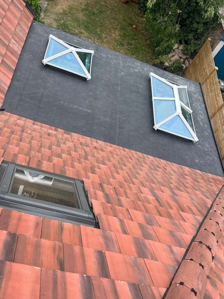 This is a photo taken from the roof ridge looking down a tiled pitched roof on to a flat roof. Works carried out by Biggin Hill Roofing Repairs